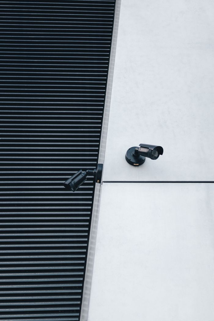 A close-up of modern surveillance cameras mounted on a sleek industrial building exterior for security.