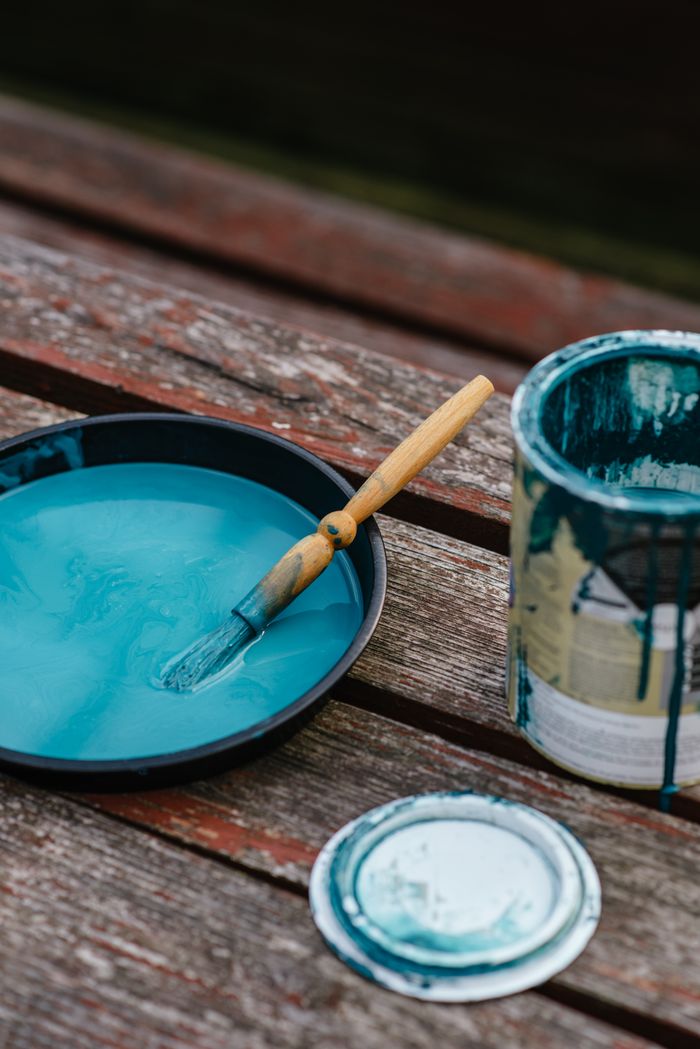 awards-img Bowl with turquoise paint and paintbrush placed on wooden surface near opened can with paint in street on black background