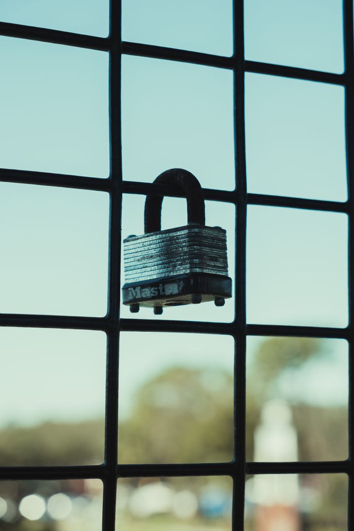 A detailed view of a padlock hanging on a metal grid fence, symbolizing security.